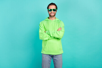 Photo of self-assured masculine cool guy crossed hands wear sunglass green sweatshirt isolated...