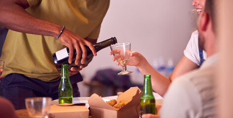 Close Up Of Man Pouring Wine For Friends Waiting For Takeaway Meal At Home