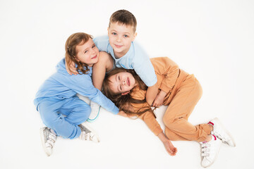 Fototapeta na wymiar Friendly children play together. Children in monochromatic clothes of delicate colors. Sporty lifestyle. Children lie on the floor and hug