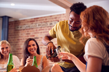 Man Pouring Wine For Friends Waiting For Takeaway Meal At Home