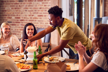 Multi-Cultural Group Of Friends Enjoying Beer And Takeaway Food At Home Together