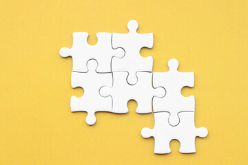 White puzzle pieces on yellow background, copy space for text.