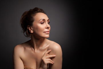 portrait of a sensual fifty year old woman on grey studio background