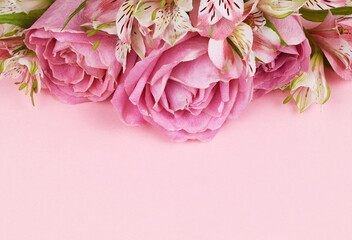 Beautiful pink rose and alstroemeria flowers in a top border on coral paper