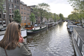 Fototapeta na wymiar An attractive tourist enjoys the view of a canal in Amsterdam.