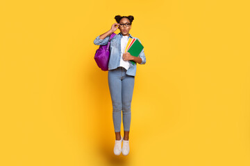 Full body photo of young african girl jump eyewear hold homework lesson isolated over yellow color...
