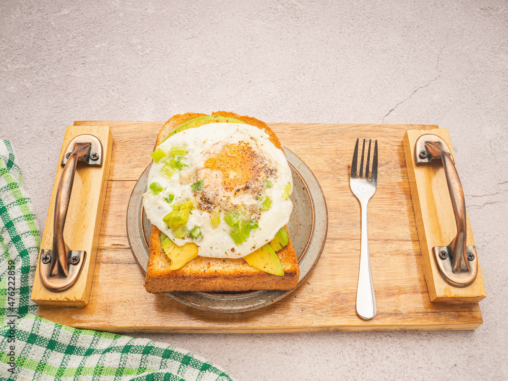 Wall mural Toast with avocado and egg served on a wooden tray