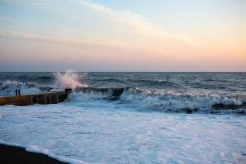 a storm on a sandy beach at dawn. a dramatic ocean landscape with a gently pink sky and frothy white waves. stormy water and crashing waves in the morning light