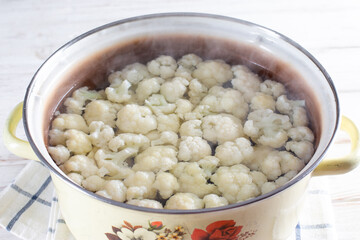 Blanched cauliflower in a saucepan on a wooden table