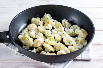 Steaming roasted cauliflower florets in a frying pan, cooking vegetables for a healthy vegetarian dish, selected focus