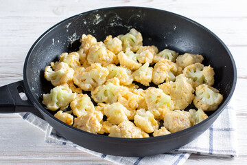 Steaming roasted cauliflower florets in a frying pan, cooking vegetables for a healthy vegetarian dish, selected focus