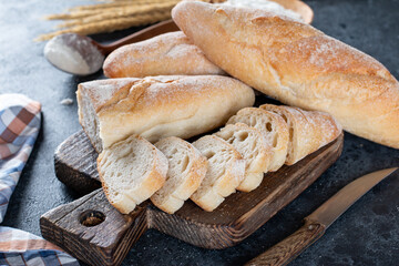 Still life with French fresh bread baguettes on a cutting board and wheat, shallow dof