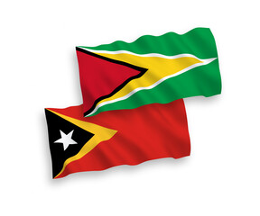 National vector fabric wave flags of Co-operative Republic of Guyana and East Timor isolated on white background. 1 to 2 proportion.