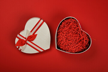 Open heart shaped gift box over red