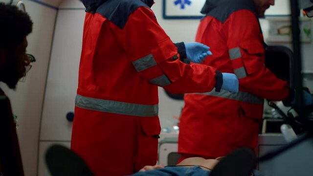 Paramedics preparing defibrillator for medical help. Doctors reanimating man