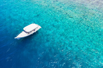 Luxury small yacht anchoring in shallow water. Aerial view of tropical island beach holiday yacht on blue reef ocean, outdoor sport, summer activity snorkeling, diving in exotic travel destination 