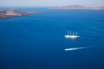 Drone view of a sailing yacht and speed boat at sea. Luxury yacht sailing in mediterranean sea bay. Arial landscape, cliffs and deep sea view. Summer recreational outdoor activity, copy space