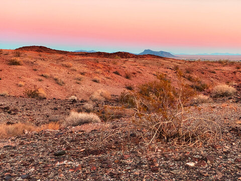 desert sunset with distance mountains in pink red orange dusk colors