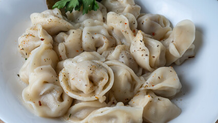 Fototapeta na wymiar Boiled meat dumplings. Close-up view of russian boiled pelmeni on white plate.