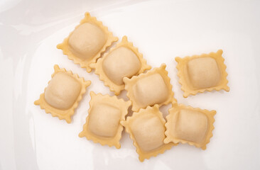 Ravioli pasta squares on a light white background.