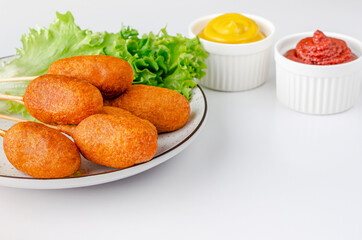 American fast food. Corn dogs on white background with mustard and ketchup. Copy space
