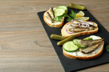 Tray with sandwiches with sprats on wooden background