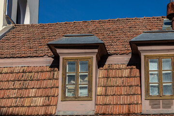 Ceramic tile roof with chimney and white wall, blue sky as background