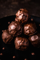 Chocolate truffles with nuts on a black plate. Coffees with chocolate ganache.