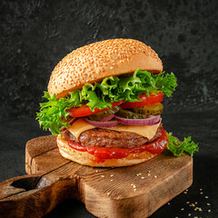 Hamburger with cheddar cheese on wooden board. Fast food concept.