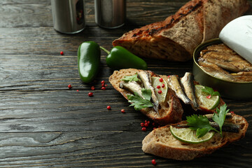 Concept of tasty snack with sandwiches with sprats on wooden background