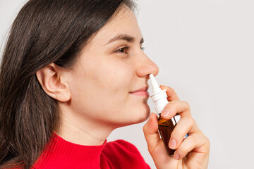 A female patient shoves a spray into the nose to treat rhinitis, an allergy with difficulty...
