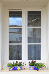 ventana blanca  con cortina de encaje con tiestos y plantas  casa de espelette pueblo vasco francés francia 4M0A8063-as21
