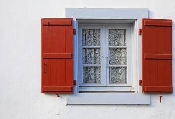 ventana gris y contraventana roja con cortina de encaje casa de espelette pueblo vasco francés...