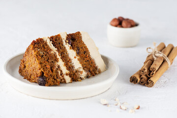 Piece of vegan carrot cake with coconut cream, blueberries, walnuts and spices on a plate.