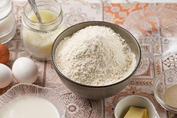 Baking ingredients for dough - white flour, eggs, milk, yeast, sugar, salt - on blue surface