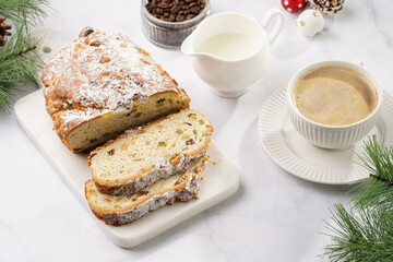 Fototapeta na wymiar White porcelain cup with coffee cappuccino on a white saucer plate and christmas pastry stollen on a marble table