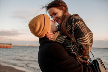 Young beautiful couple on a walk by the sea in autumn in the off-season, hugging, walking, smiling