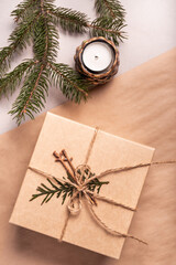 Fototapeta na wymiar Packing a gift for Christmas and new year in eco-friendly materials: kraft paper, live fir branches, cone, twine, tied with a bow. Tags with mock up, natural decor, hand made, flatlay.