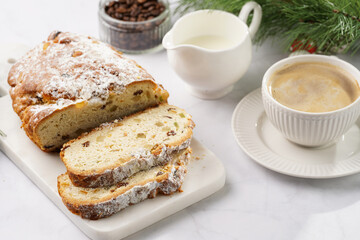 White porcelain cup with coffee cappuccino on a white saucer plate and christmas pastry stollen on...