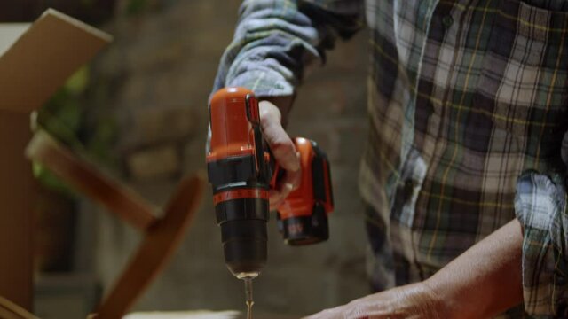 Mature woman carpenter screwing a screw on a wood board