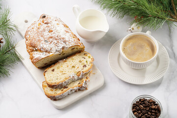 White porcelain cup with coffee cappuccino on a white saucer plate and christmas pastry stollen on a marble table