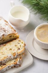 White porcelain cup with coffee cappuccino on a white saucer plate and christmas pastry stollen on a marble table