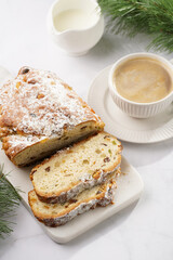 White porcelain cup with coffee cappuccino on a white saucer plate and christmas pastry stollen on a marble table