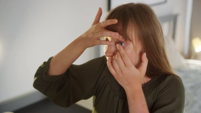 Young Woman Placing Contact Lens on Her Eye in Front of Mirror, Close Up. Vision Correction Device, Full Frame