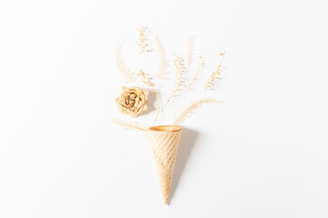 Waffle cone with dried flowers and leaves on white background. Flat lay, top view, floral background. Spring, summer concept.