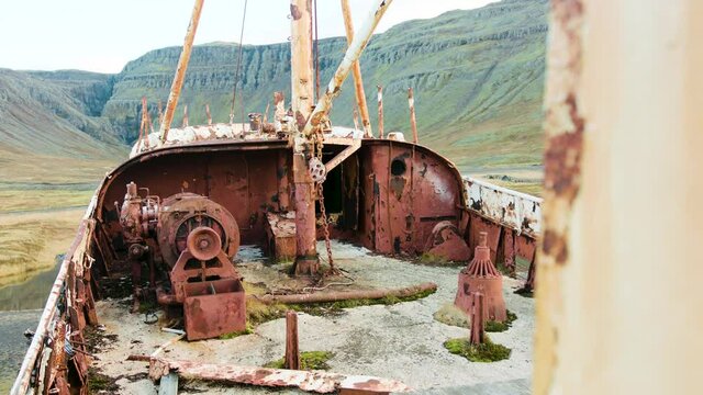 A view of the crumbling and corroded deck of a shipwreck and the perfect landscape in the background