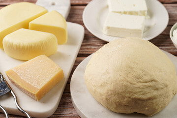 Various cheese types on marble and porcelain plates and fresh dough - ingredients for traditional georgian open pie khachapuri