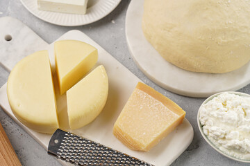 Various cheese types on marble and porcelain plates and fresh dough - ingredients for traditional...