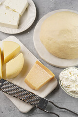 Various cheese types on marble and porcelain plates and fresh dough - ingredients for traditional georgian open pie khachapuri