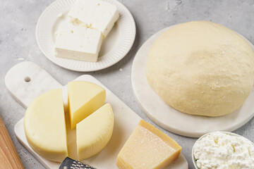 Various cheese types on marble and porcelain plates and fresh dough - ingredients for traditional georgian open pie khachapuri